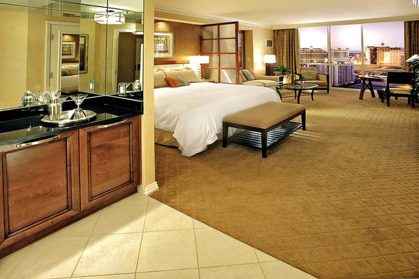 Innenansicht einer Suite im The Signature at MGM Grand mit großem Bett, Wohnzimmer und Blick auf die Stadt.