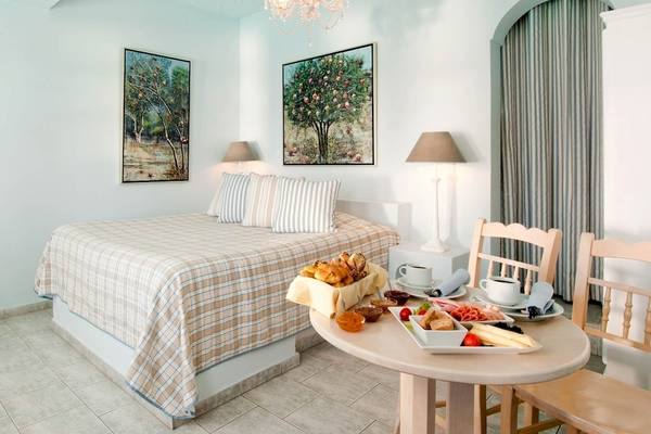 Schlafzimmer im Andromeda Villas & Spa Resort mit Bett, Frühstückstisch und Dekor.