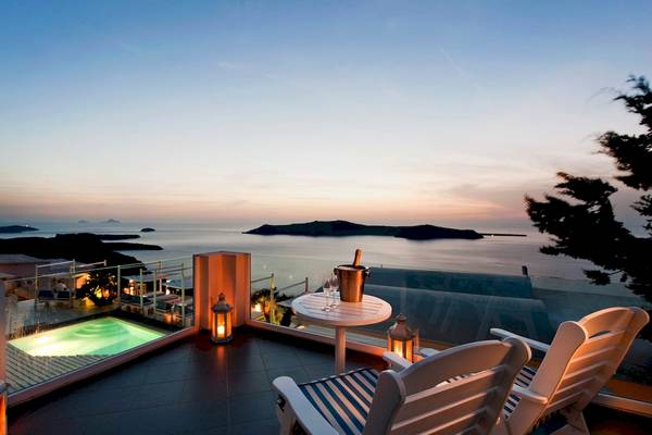 Terrasse mit Meerblick am Abend mit Swimmingpool, Flasche und Gläsern.