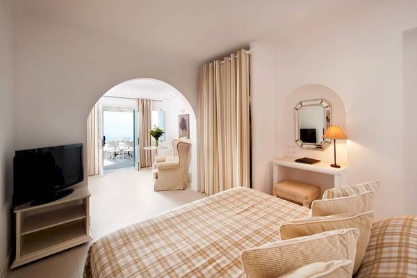 Innenansicht eines Schlafzimmers im Andromeda Villas & Spa Resort mit einem Bett, Fernseher und einem kleinen Balkon.