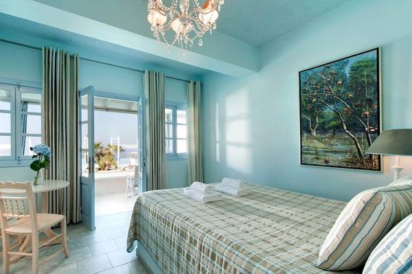 Schlafzimmer im Andromeda Villas & Spa Resort mit blauen Wänden, Bett, Tisch, Stühlen und Aussicht.