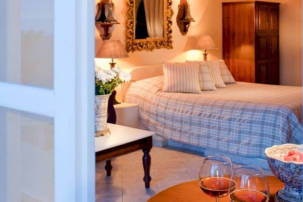 Schlafzimmer im Andromeda Villas & Spa Resort mit Bett, Tisch, Wein und Obst