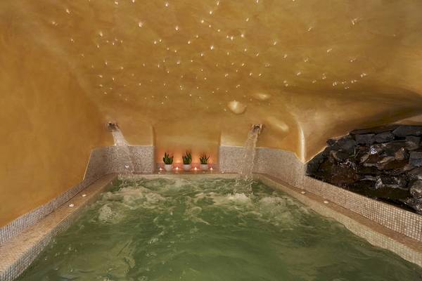 Innenpool im Andromeda Villas & Spa Resort mit Wasser, Pflanzen und beleuchteten Wänden.