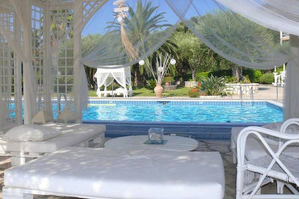 Pool-Loungebereich im Nefeli Hotel mit weißen Möbeln und Vorhängen.