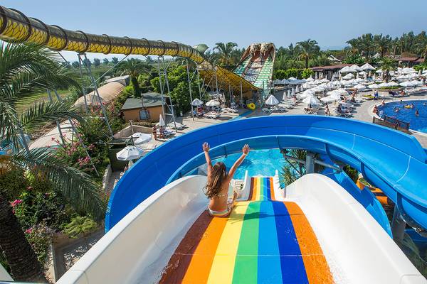 Ein Mädchen rutscht auf einer regenbogenfarbenen Wasserrutsche im Crystal Paraiso Verde Resort.