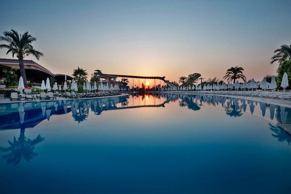 Der Pool des Crystal Paraiso Verde Resorts & Spa bei Sonnenuntergang mit Sonnenlichtreflexionen.