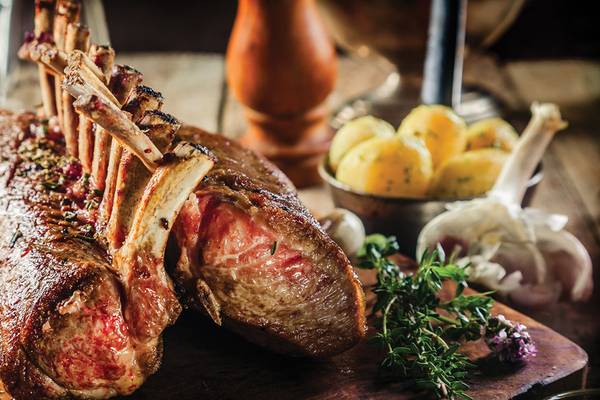 Gebratenes Lamm mit Kartoffeln und Knoblauch auf einem Holzschneidbrett.