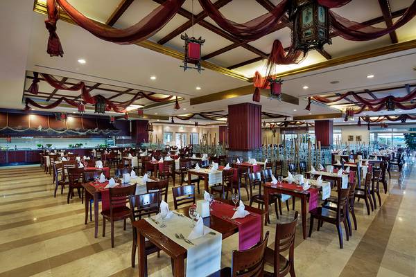 Innenansicht des Restaurants im Crystal Paraiso Verde Resort & Spa mit gedeckten Tischen und dekorativen Deckenlampen.