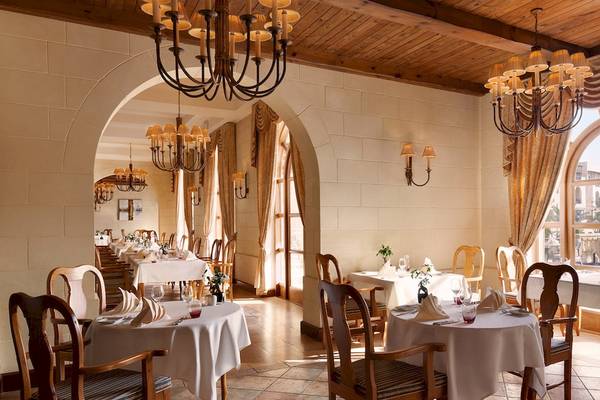 Restaurant im Kempinski Hotel San Lawrenz Malta mit gedeckten Tischen, Kronleuchtern und großen Fenstern.