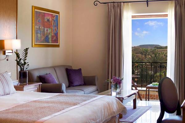 Innenansicht eines Hotelzimmers im Kempinski Hotel San Lawrenz Malta mit Blick auf die Landschaft.