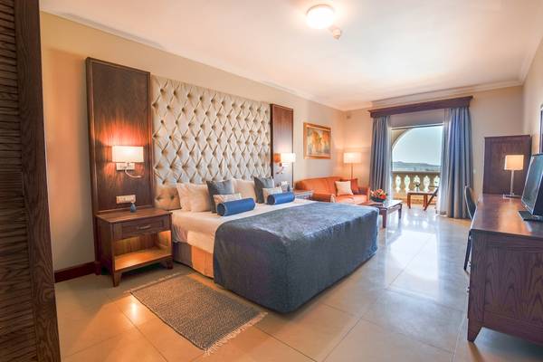 Hotelzimmer im Kempinski Hotel San Lawrenz Malta mit Bett, Nachttischen, Wohnzimmer und Aussicht.