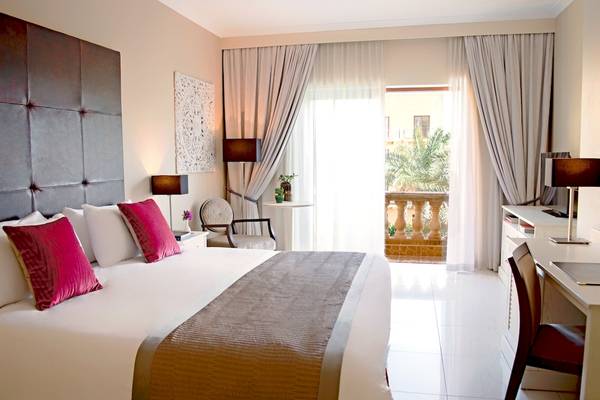 Schlafzimmer im Kempinski Hotel San Lawrenz Malta mit Bett, Kissen, Lampen und Balkon
