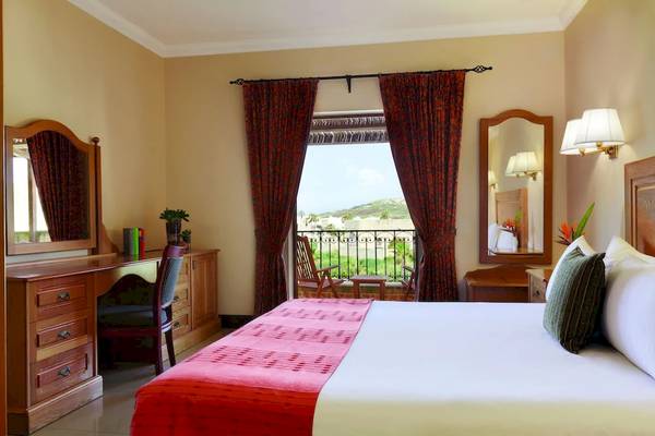 Hotelzimmer im Kempinski Hotel San Lawrenz Malta mit Balkon, Bett, Schreibtisch und Möbeln.