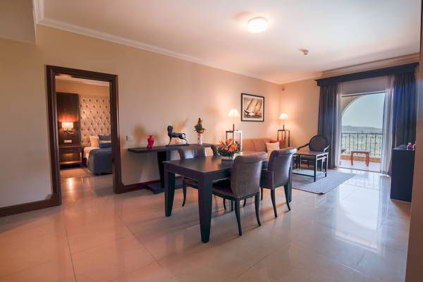 Mahlzeitbereich im Kempinski Hotel San Lawrenz Malta mit Tisch, Stühlen und Blick auf das Gelände.