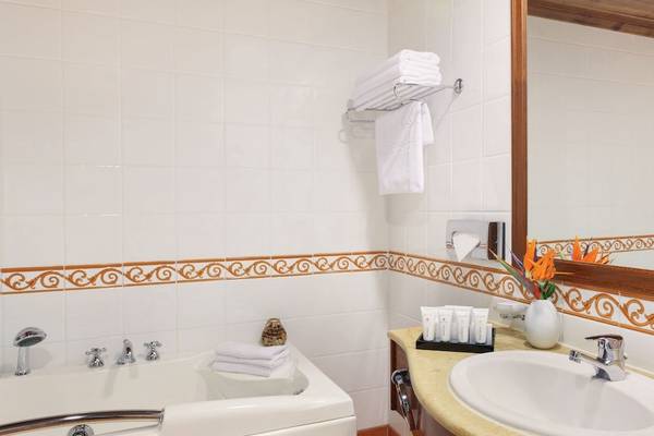 Badezimmer im Kempinski Hotel San Lawrenz Malta mit Badewanne, Waschbecken, Spiegel und Dekoration.