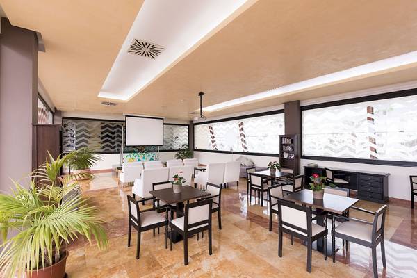 Innenbereich des AluaSoul Costa Adeje Hotels mit Möbeln, Pflanzen und Projektor