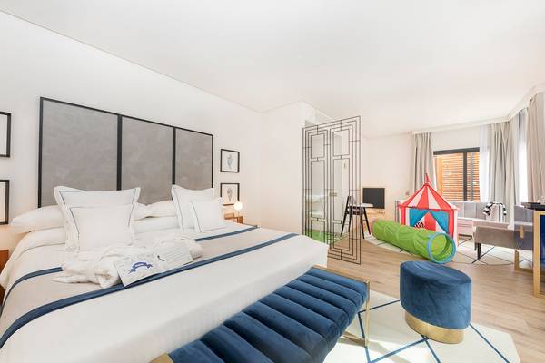 Kinderzimmer im AluaSoul Costa Adeje Hotel mit einem großen Bett, Kissen, Spielzeug und einem separaten Spielbereich.