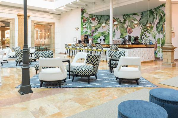 Lobby des Be Live Experience La Nina Hotels mit blauen Teppichen und tropischen Wandmalereien.