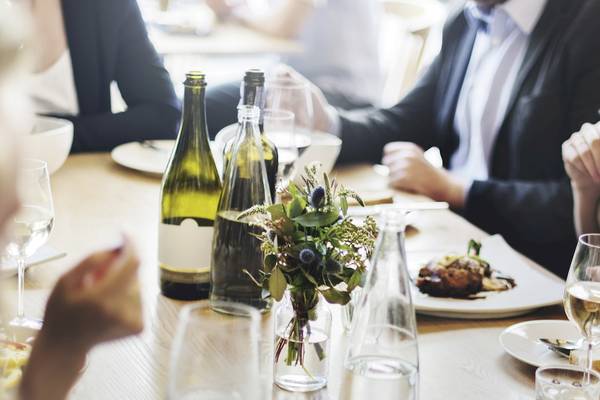 Geschäftsessen am Tisch mit Flaschen, Wein, Gläsern und Speisen.