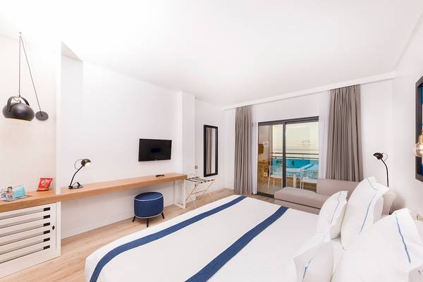 Innenansicht eines Hotelzimmers im AluaSoul Costa Adeje mit Bett, Schreibtisch und Poolsicht