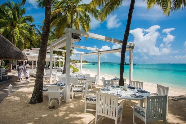 Außenbereich des Constance Belle Mare Plage Hotels mit weißen Stühlen und Tischen auf dem Strand