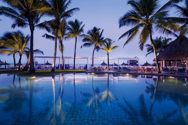 Abendansicht des Constance Belle Mare Plage Hotels mit Swimmingpool und Palmen
