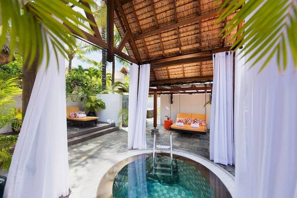 Außenpoolbereich im Constance Belle Mare Plage Hotel mit Loungebereich und tropischen Pflanzen.