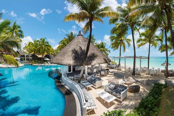 Außenpoolbereich des Constance Belle Mare Plage Hotels mit Sonnenliegen und Blick auf das Meer.