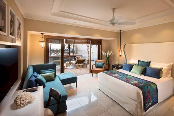Suite-Schlafzimmer im Constance Belle Mare Plage mit großem Bett, Couch, Fernseher und Deckenventilator.
