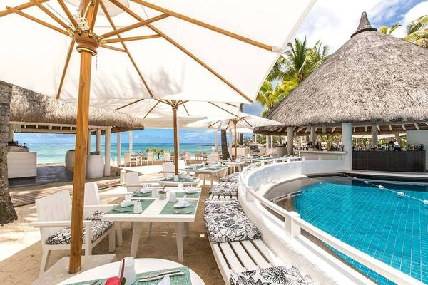 Außenrestaurant mit Tischen, Stühlen und Sonnenschirmen neben einem Pool im Constance Belle Mare Plage.