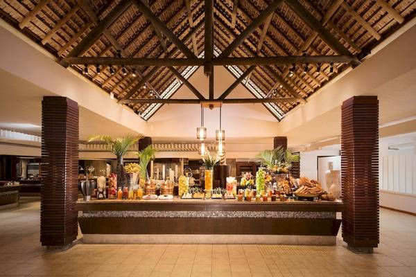 Buffetbereich im Constance Belle Mare Plage Hotel mit üppigen Früchten und Getränken.