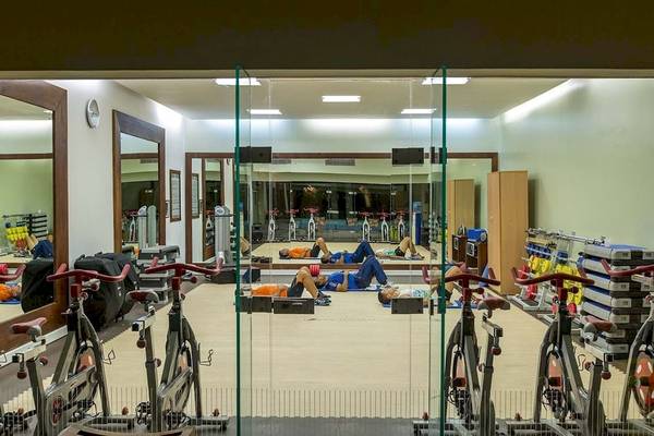 Fitnessstudio im Constance Belle Mare Plage Hotel mit Menschen, die auf Matten liegen und auf Fahrrädern trainieren.