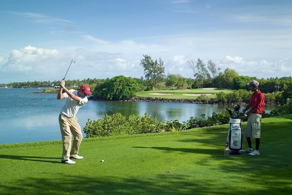 Golfer spielt am Wasser im Constance Belle Mare Plage Hotel.