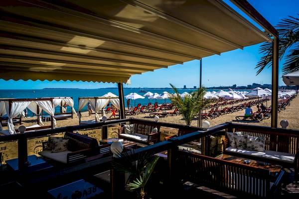 Aussicht von der Terrasse des Helena Sands Hotels auf den Strand mit Sonnenschirmen und Liegestühlen.