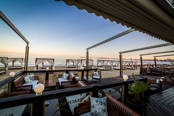 Terrasse des Helena Sands Hotels mit Blick auf das Meer und Loungemöbeln.
