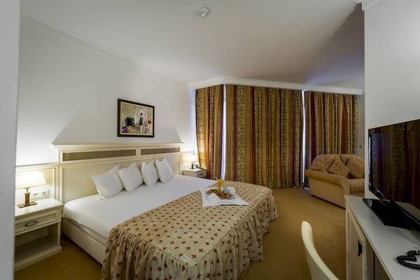 Helena Sands Hotelzimmer mit Bett, Couch, Fernseher und Frühstückstablett