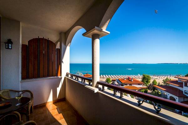 Ein Balkon mit Blick auf das Meer im Helena Sands Hotel mit einem Glas Wein auf dem Tisch.