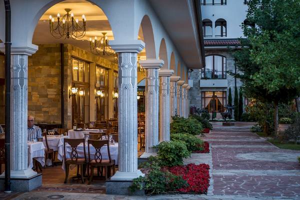 Terrasse des Helena Sands Hotels mit Säulen, Tischen und Stühlen.