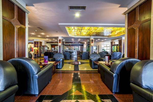 Lobbybereich des Helena Sands Hotels mit schwarzen Ledersesseln und einem farbenfrohen Bodenmuster.