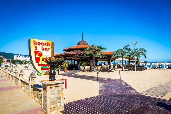 Strandbar der Helena Sands Hotel mit bunter Beschilderung und Blick auf das Meer.