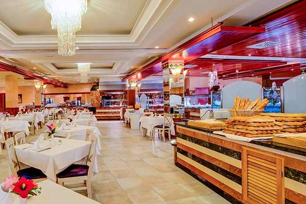 Innenansicht des Restaurants im SBH Costa Calma Beach Resort mit vielen Tischen und Stühlen, gedeckten Tischen, und einer Theke mit Brot und Backwaren.