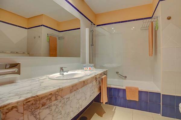 SBH Costa Calma Beach Resort Badezimmer mit Marmor-Waschtisch, Dusche und Badewanne.