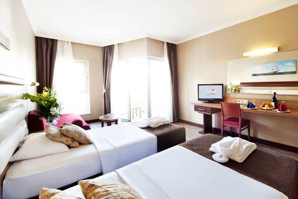 Hotelzimmer im Sueno Hotels Beach Side mit zwei Betten, Fernseher und Schreibtisch.