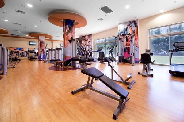 Fitnessbereich im Sueno Hotels Beach Side mit diversen Trainingsgeräten und großen Fenstern.
