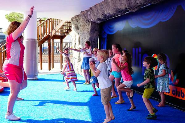 Kinderanimation im Sueno Hotels Beach Side mit einer Gruppe Kindern und einer Animateurfrau.