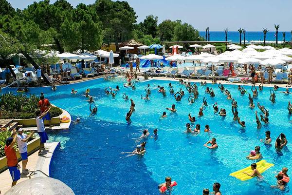 Poolbereich im Sueno Hotels Beach Side mit vielen Gästen und Sonnenschirmen