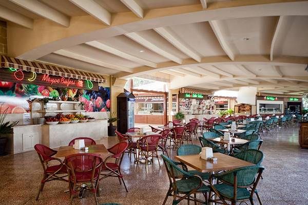 Innenbereich eines Restaurants im Sueno Hotels Beach Side mit runden Tischen und Stühlen.