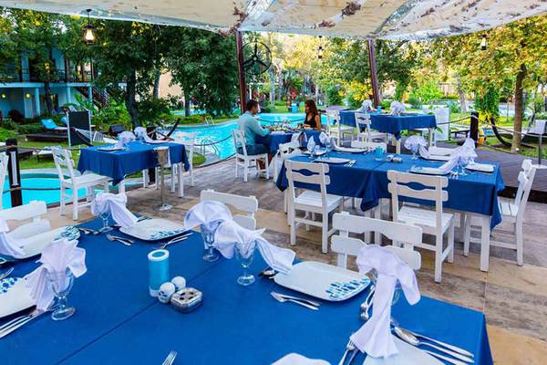 Restaurantbereich im Freien im Sueno Hotels Beach Side mit blauen Tischdecken und Blick auf den Pool.
