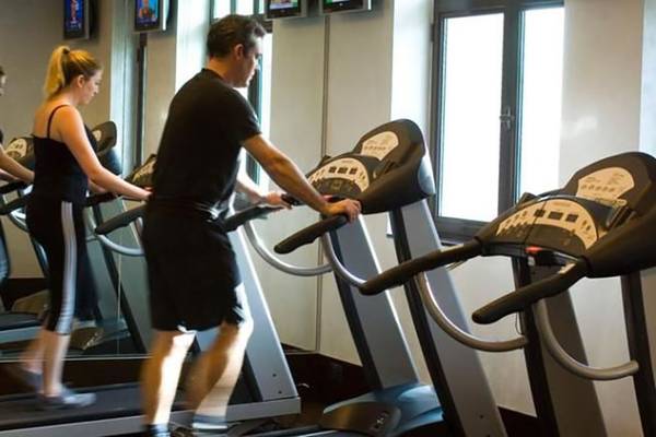 Fitnesscenter im Manzil Downtown Hotel in Dubai mit mehreren Personen auf Laufbändern.