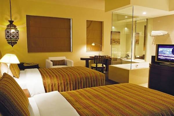 Doppelbett Zimmer im Manzil Downtown Hotel, Dubai mit Badewanne und Fernseher.